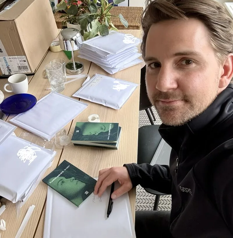 En av författarna signerar och packar exemplar av boken